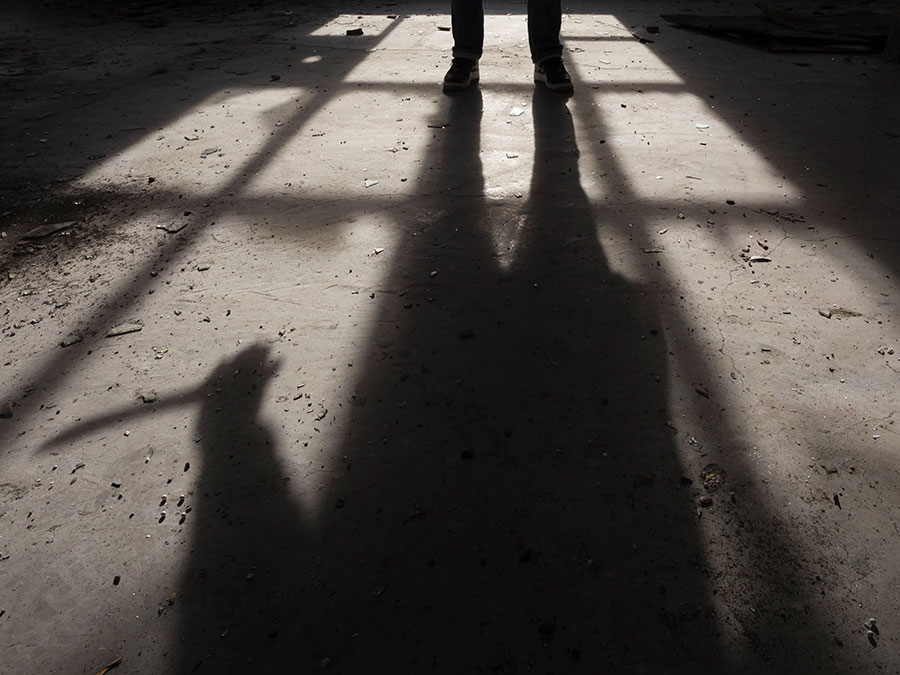 Shadow of a man holding large knife in his hand inside of some dark, spooky buiding